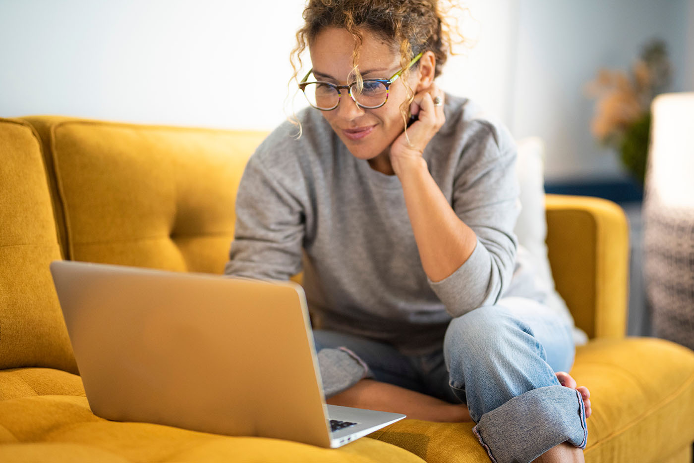 Frau sitzt auf dem Sofa vor Laptop