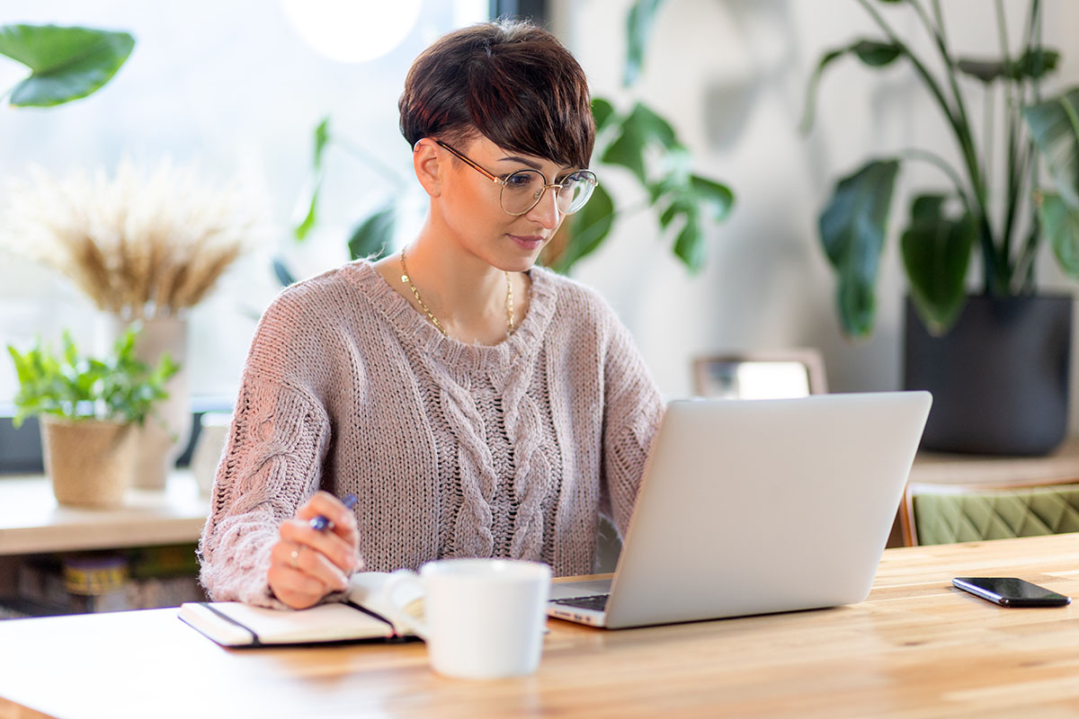 Frau, die im Büro am Laptop die Jahresmeldung macht