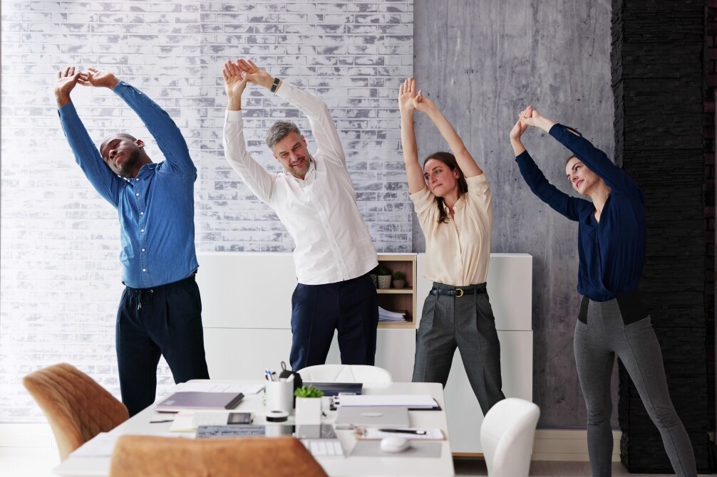 Mitarbeitende dehnen sich gemeinsam im Meeting.