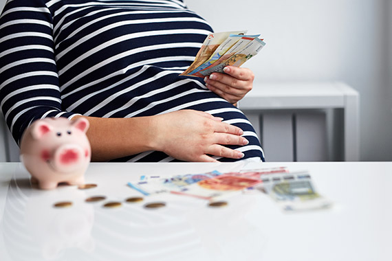 Hochschwangere Frau mit Geld in der Hand